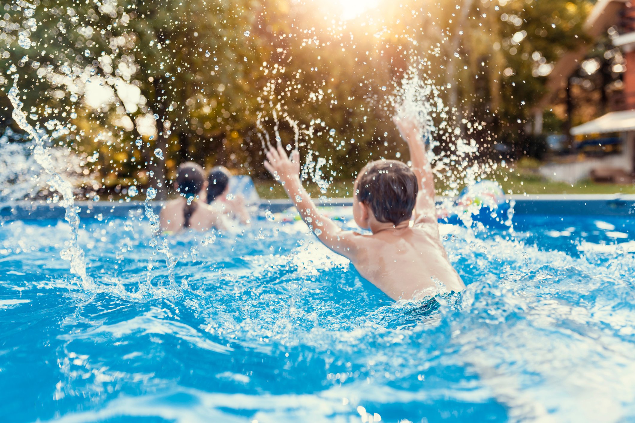 Kids playing and splashing in a pool.