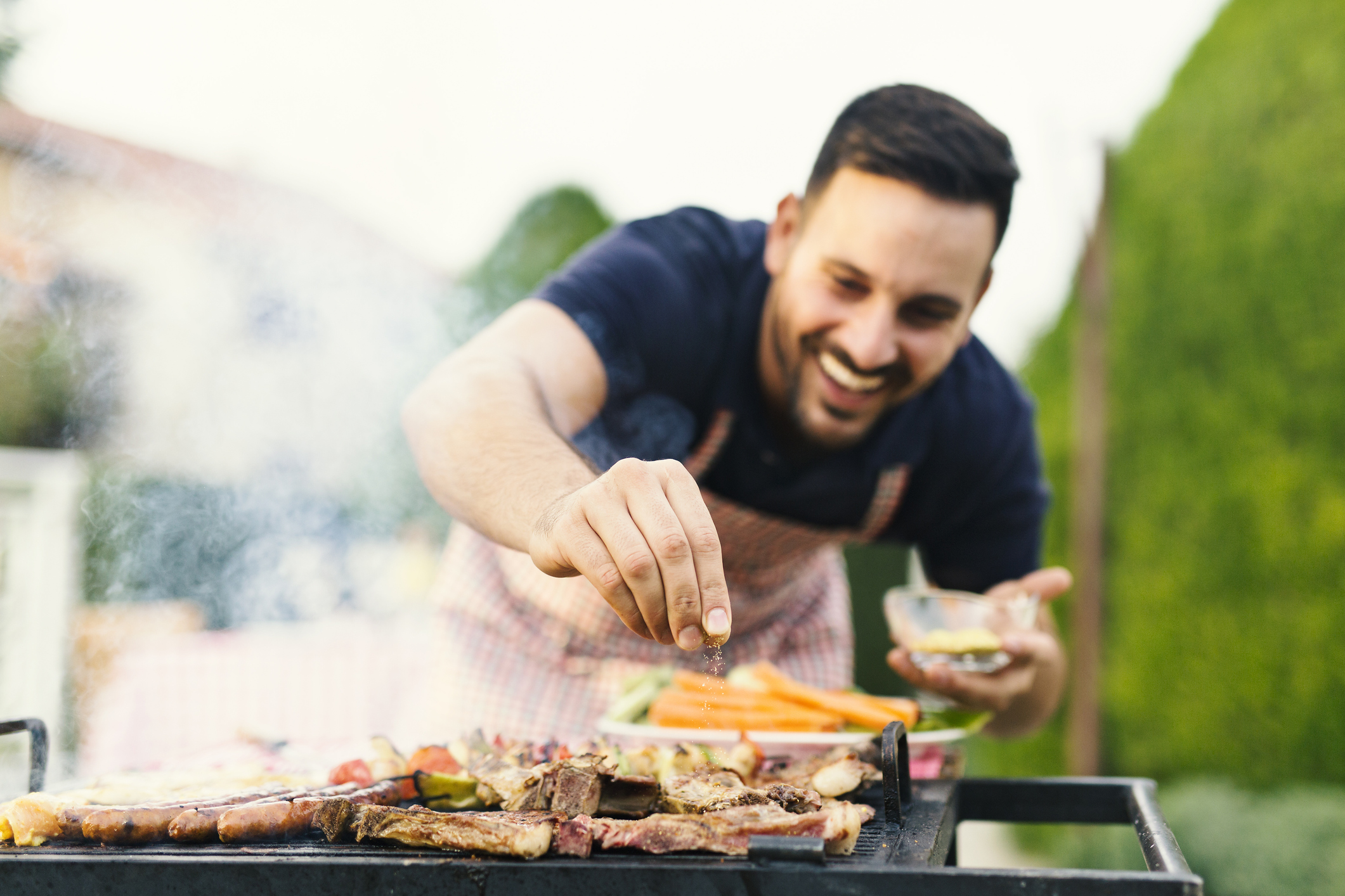 seasoning your grill - smiling man grilling outdoors