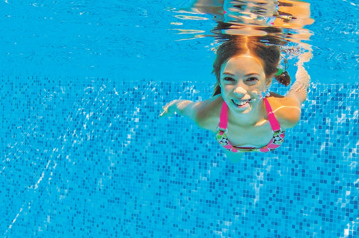 pool water test kit - how often should I test my pool water - young girl underwater in a clean pool